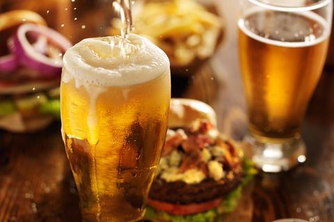 Volles Bierglas auf Esstisch mit Fast Food
