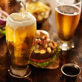 Volles Bierglas auf Esstisch mit Fast Food