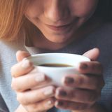 Junge Frau genießt den Geruch ihres Kaffees