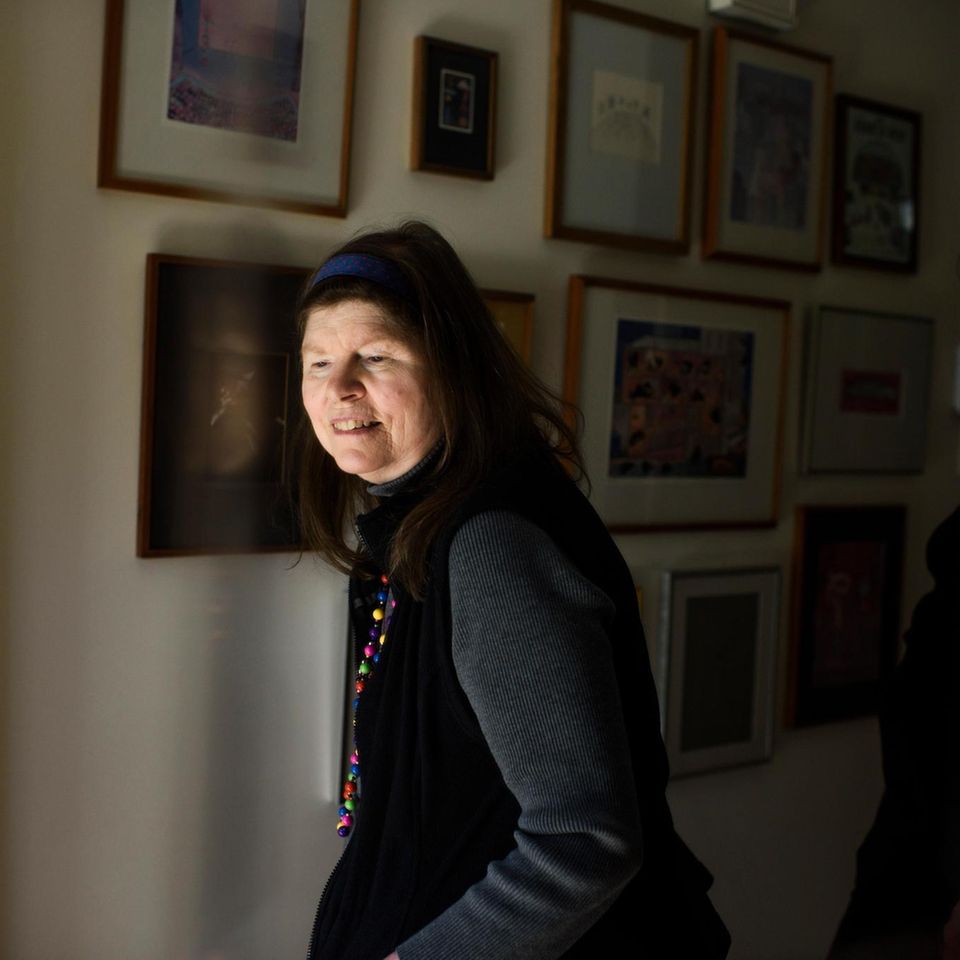 Lonni Sue vor einer Wand mit ihren Gemälden