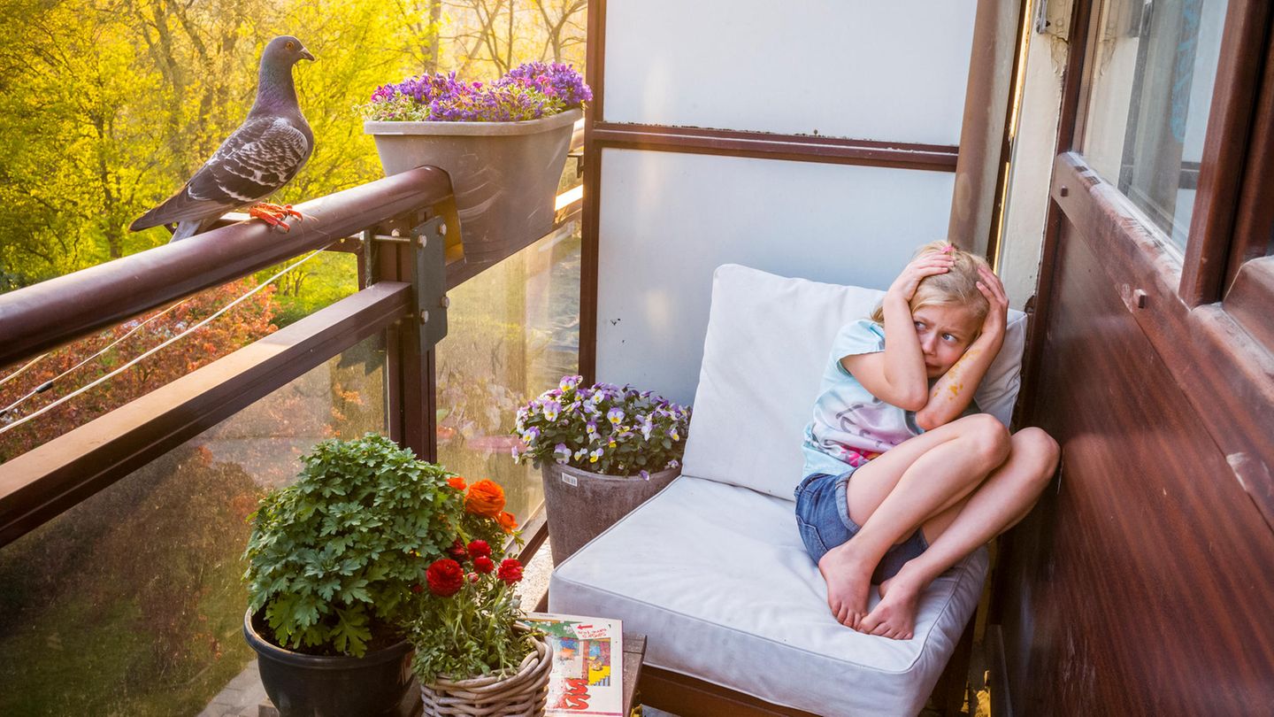 Mädchen erschreckt sich vor Taube auf dem Balkon
