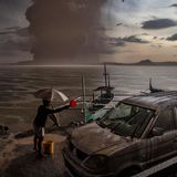 Ein Bewohner von Talisay in Batangas wäscht ein Auto ab, das mit Vulkanasche und Regen bedeckt