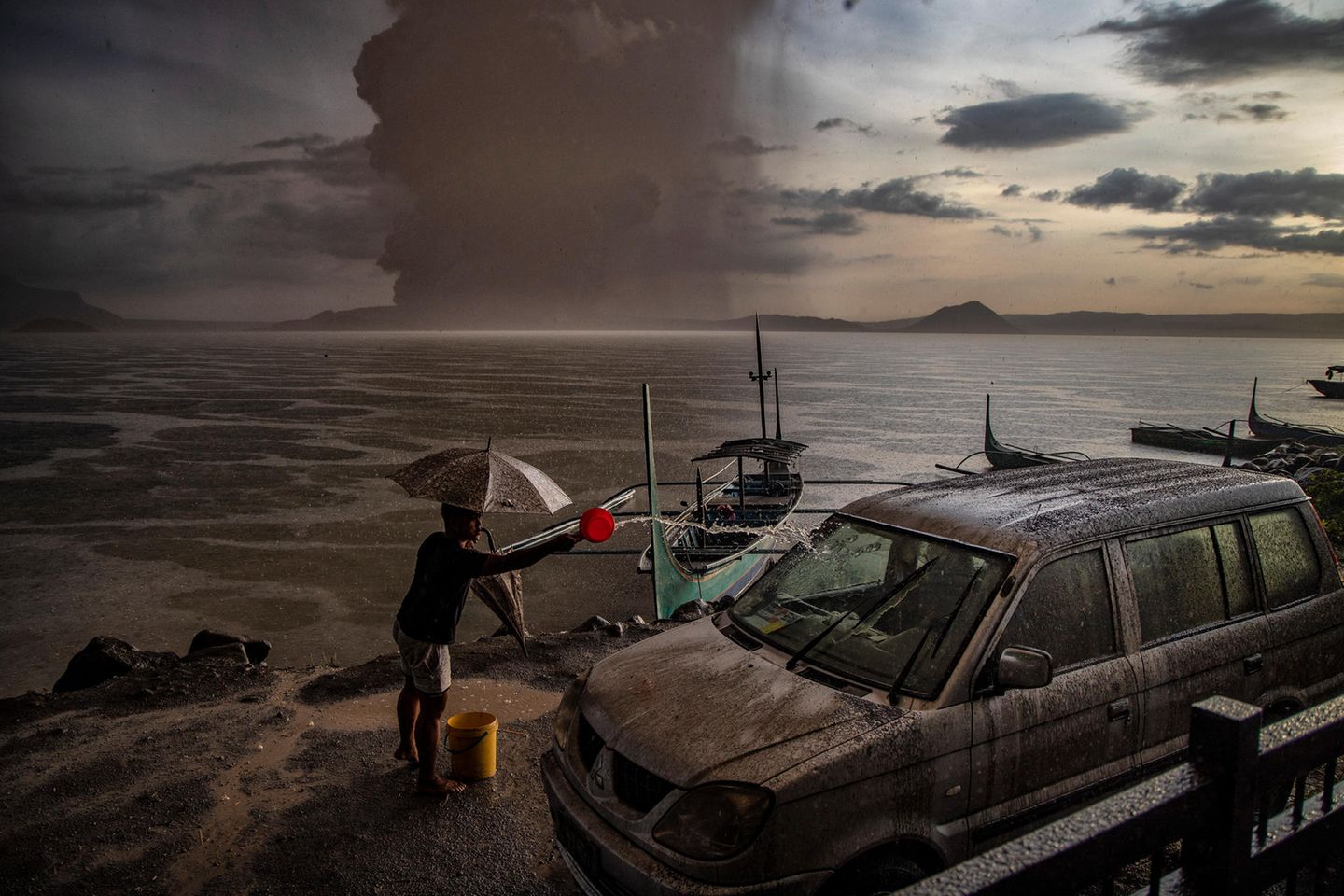 Der Vulkanausbruch Ein Bewohner von Talisay in Batangas wäscht ein Auto ab, das mit Vulkanasche und Regen bedeckt
