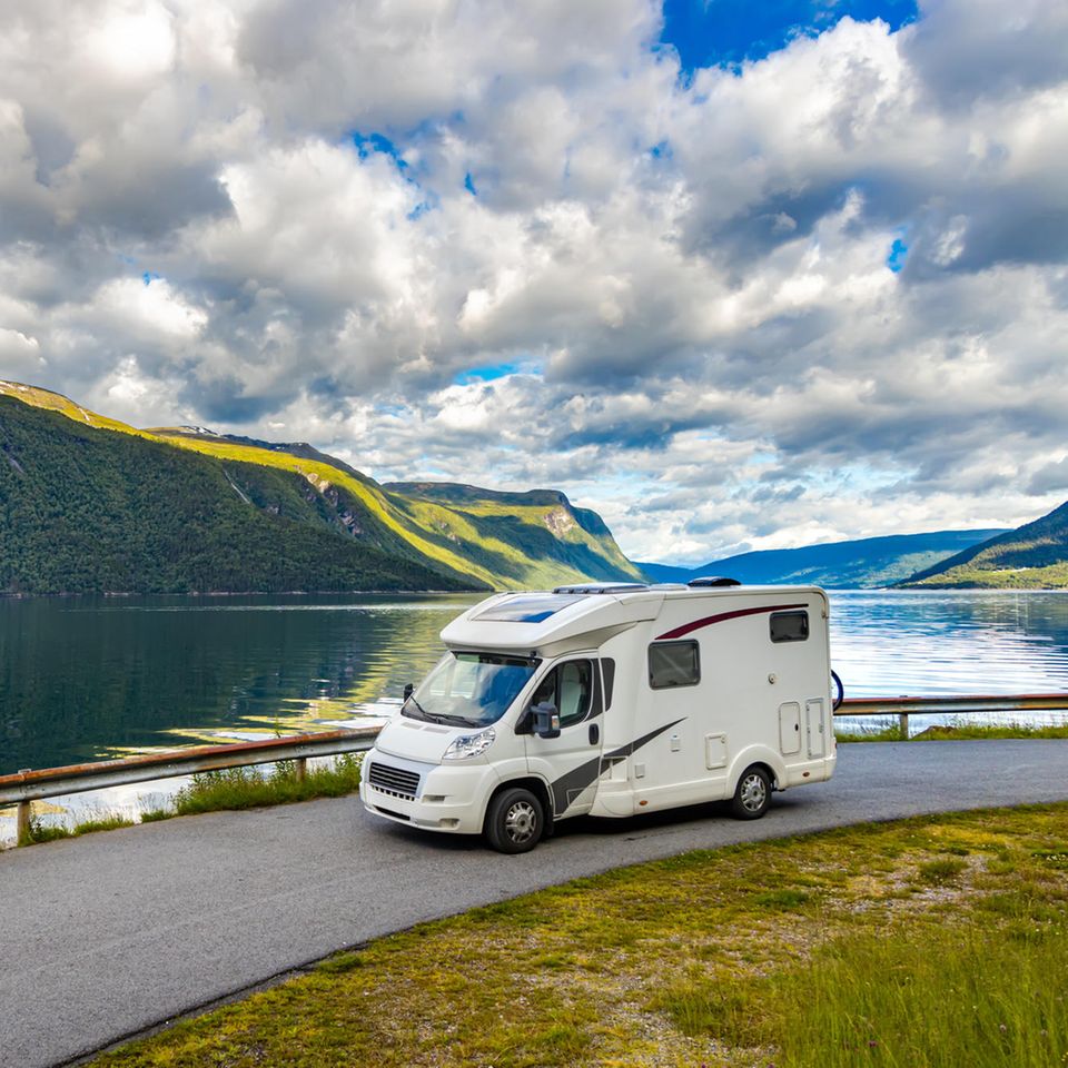 Wohnmobil fährt auf einer Straße mit See im Hintergrund