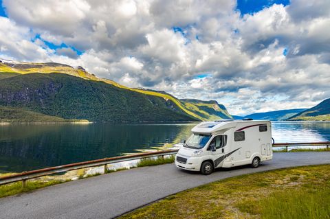 Wohnmobil fährt auf einer Straße mit See im Hintergrund