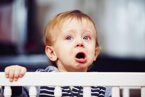 Kleiner Junge weint im Gitterbett