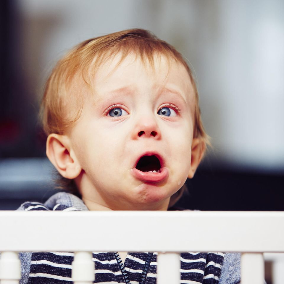 Kleiner Junge weint im Gitterbett