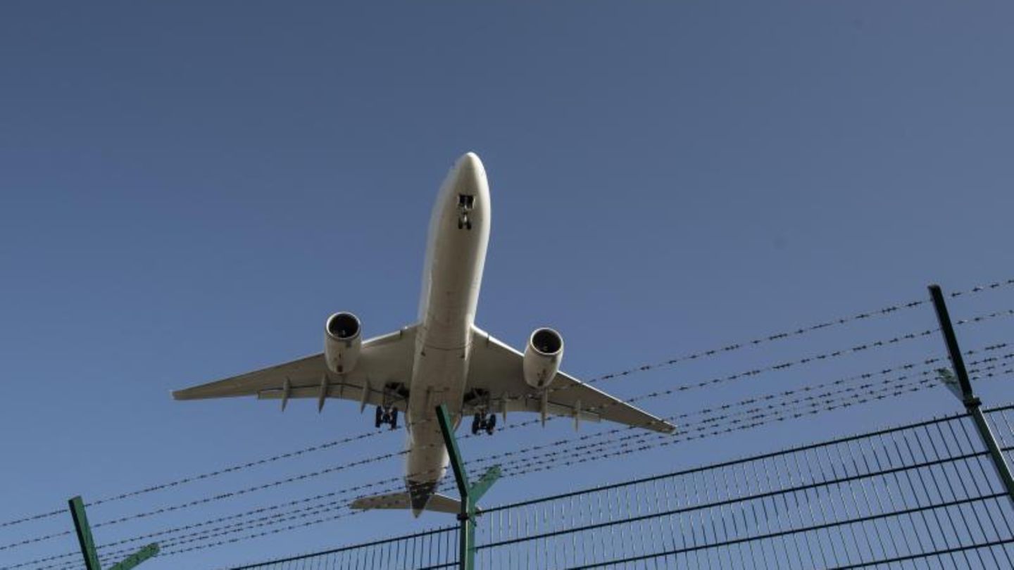 Flugzeug fliegt über einen Zaun