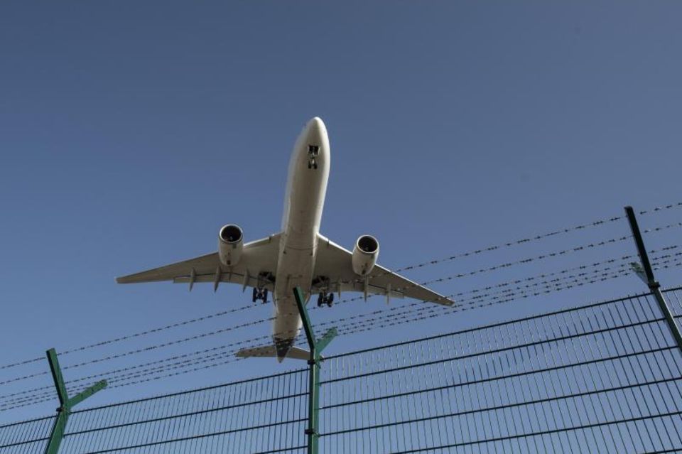 Flugzeug fliegt über einen Zaun