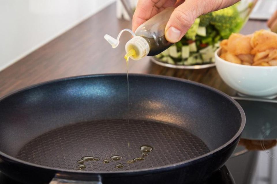 Beim Kochen wird Öl in eine beschichtete Pfanne gegossen