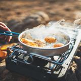 Person brät Eier auf einem Campingkocher