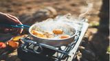 Person brät Eier auf einem Campingkocher