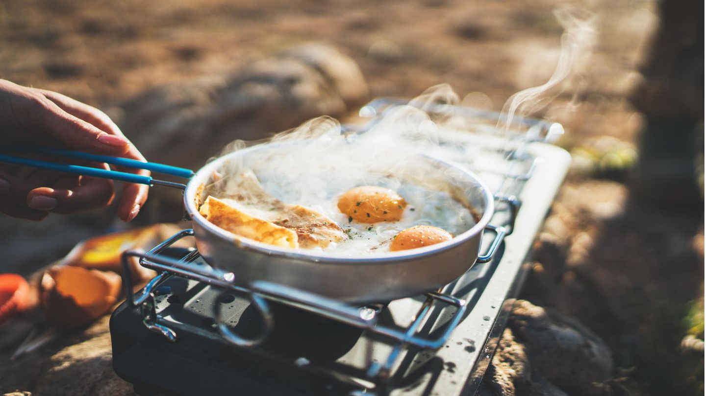 Person brät Eier auf einem Campingkocher