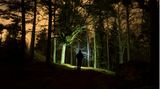 Mann wandert mit Taschenlampe durch die Dunkelheit im Wald