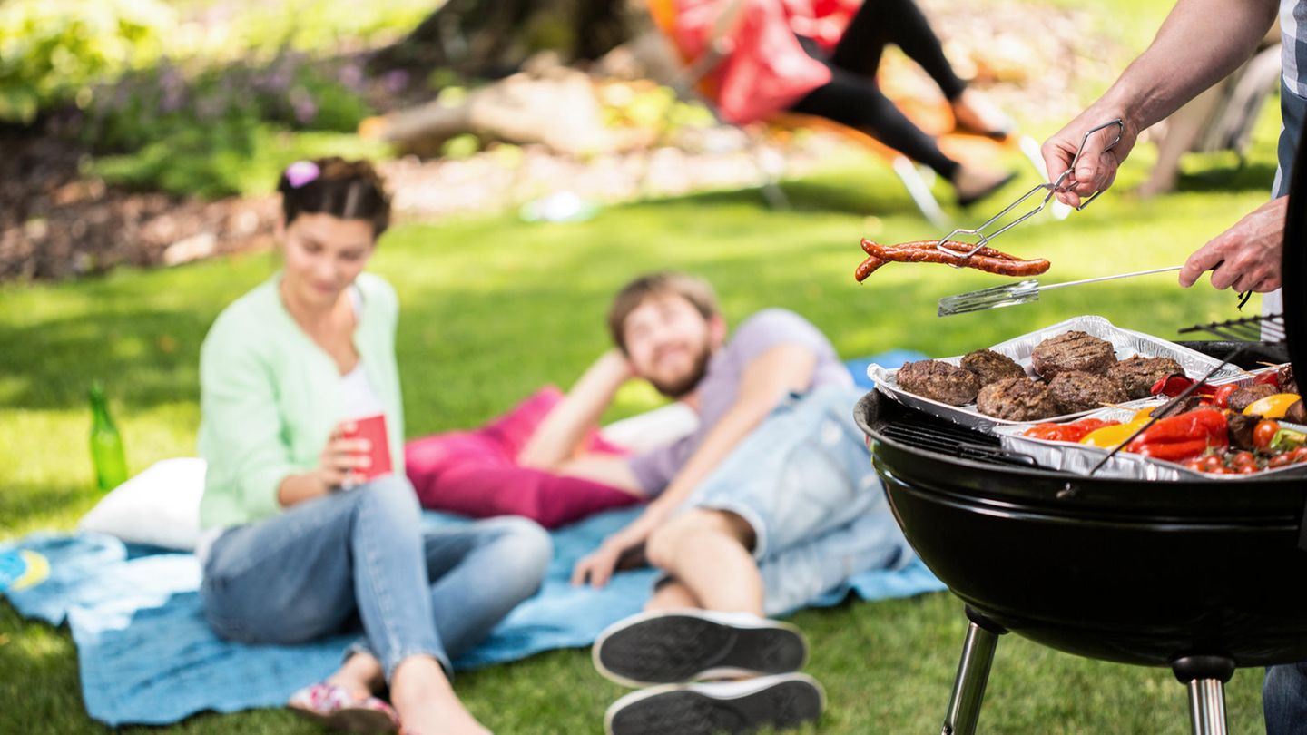 Zwei Menschen liegen im Park und im Vordergrung ist ein Grill