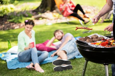 Zwei Menschen liegen im Park und im Vordergrung ist ein Grill