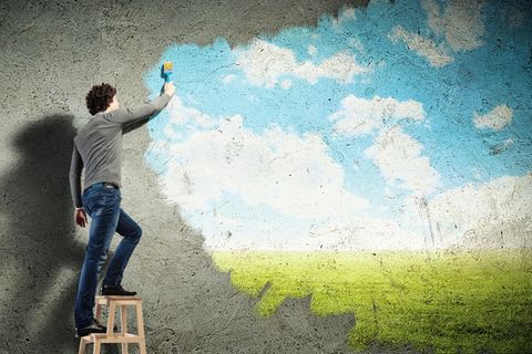 Mann auf einer Leiter malt ein Wandbild