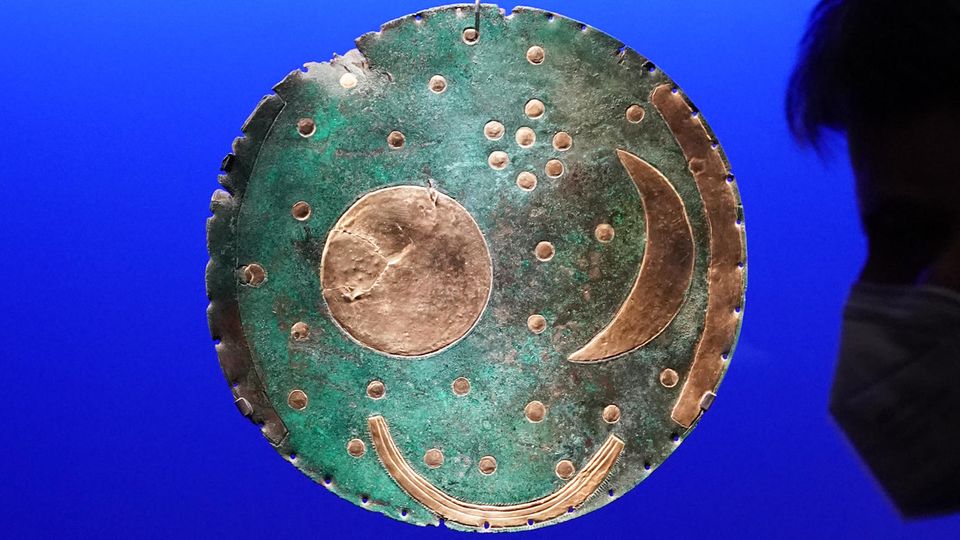 Die Himmelsscheibe (o.) von Nebra mit dem gesamten Fundstand betrachtet ein Besucher in der Ausstellung „Die Welt der Himmelsscheibe von Nebra - Neue Horizonte“ im Landesmuseum Halle