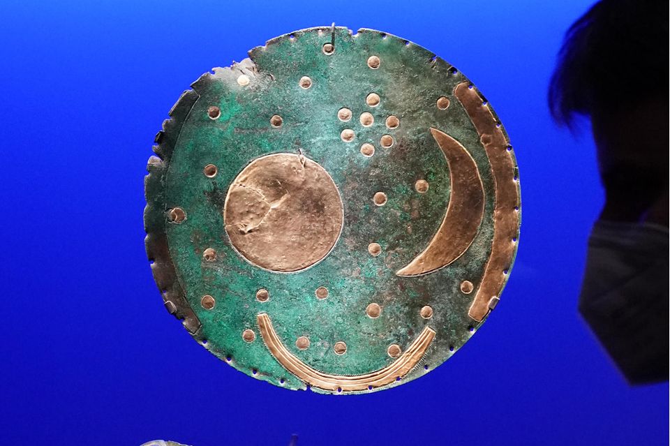 Die Himmelsscheibe (o.) von Nebra mit dem gesamten Fundstand betrachtet ein Besucher in der Ausstellung „Die Welt der Himmelsscheibe von Nebra - Neue Horizonte“ im Landesmuseum Halle