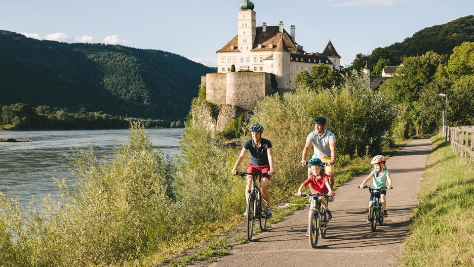 Eine Familie radelt auf dem Donauradweg an Schloss Schönbiel vorbei