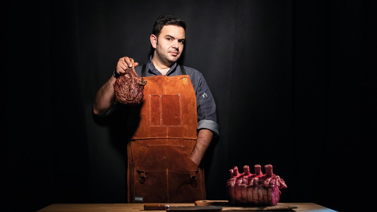 Küchenchef Mateo hält ein Beil und ein Stück Fleisch in der Hand