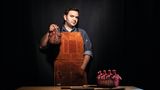 Küchenchef Mateo hält ein Beil und ein Stück Fleisch in der Hand