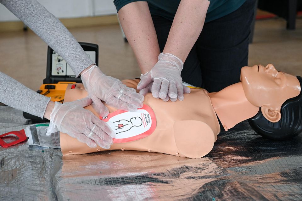 Ausbilderinnen vom Arbeiter-Samariter-Bund (ASB) demonstrieren an einer Reanimationspuppe in einem Ersthelferkurs die Wiederbelebung mit Einsatz eines Defibrillators