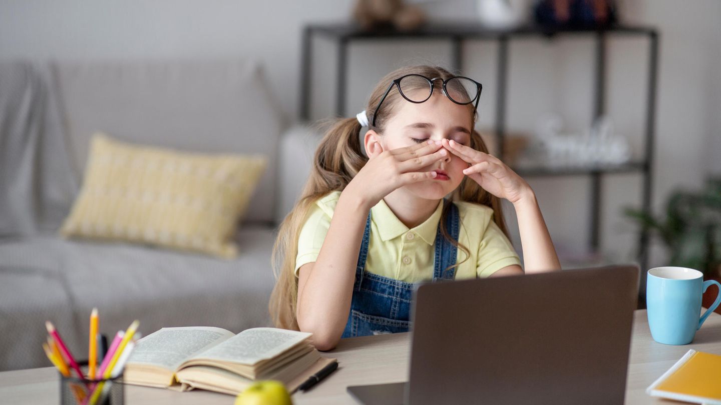 Mädchen sitzt vor dem PC und reibt sich die Augen