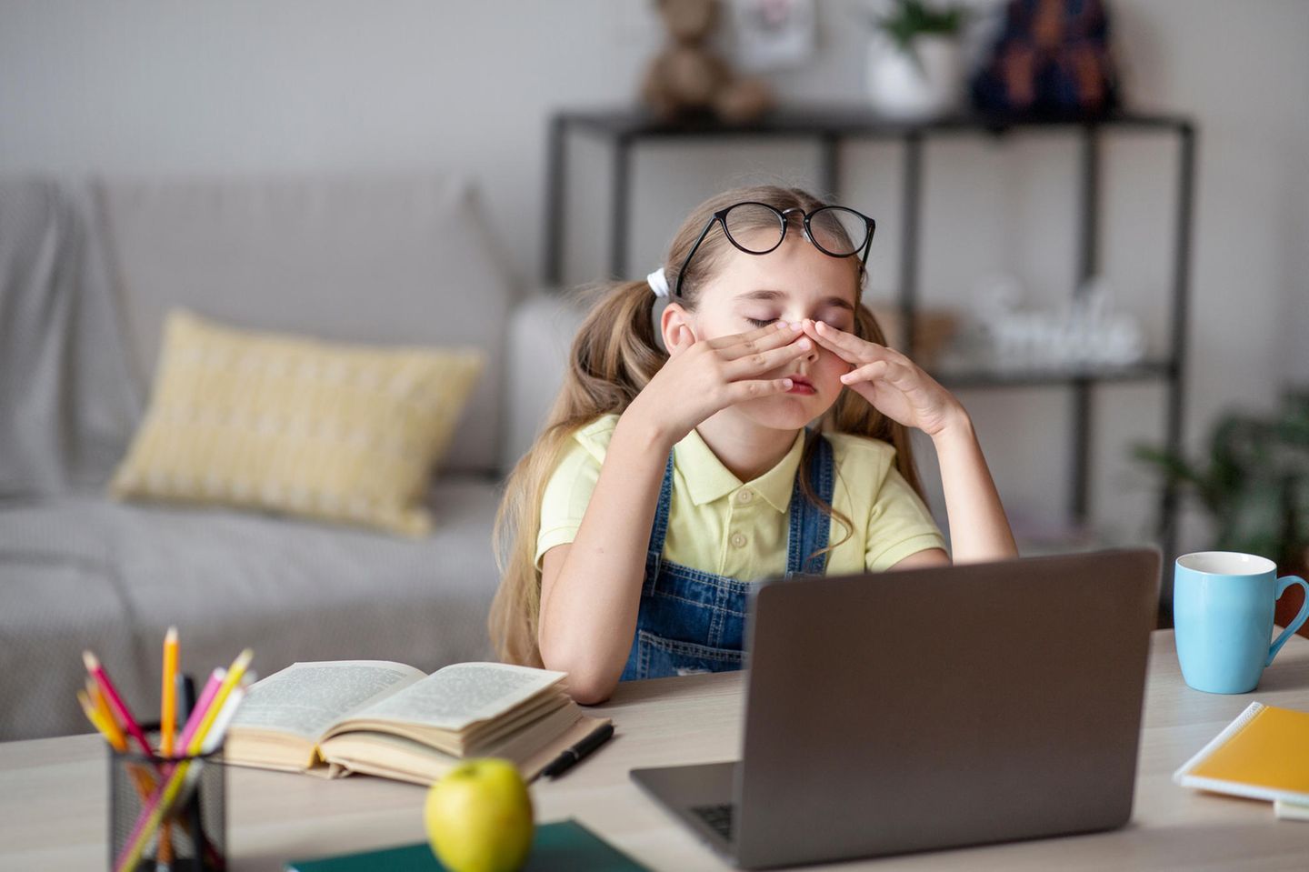 Mädchen sitzt vor dem PC und reibt sich die Augen