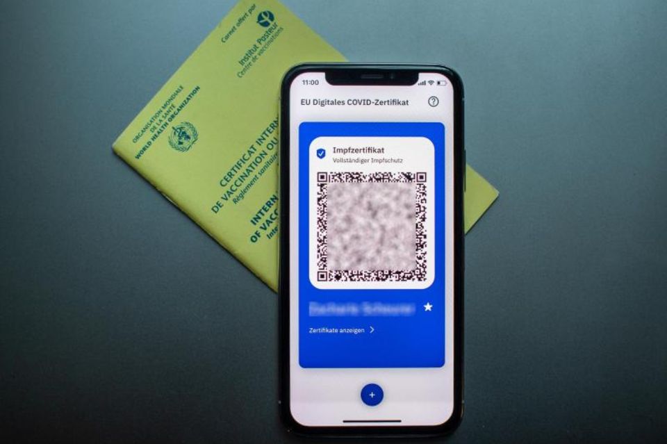 Impfpass un digitaler Impfpass auf dem Handy liegen auf dem Tisch