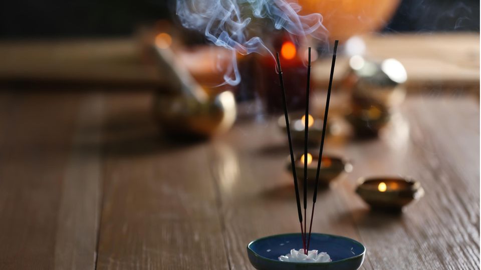 Rauchende Räucherstäbchen auf einem Holztisch mit Kerzen