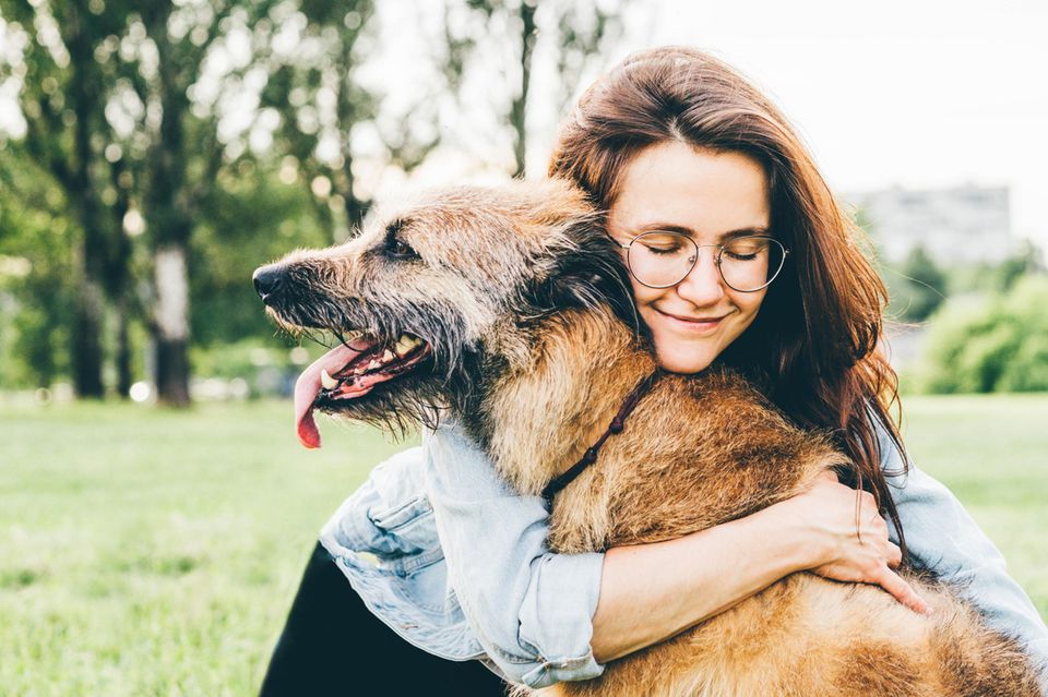 Lächelnde Frau umarmt ihren Hund