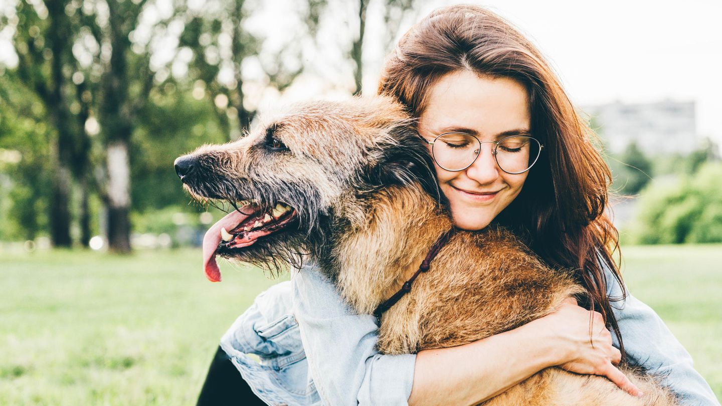 Lächelnde Frau umarmt ihren Hund
