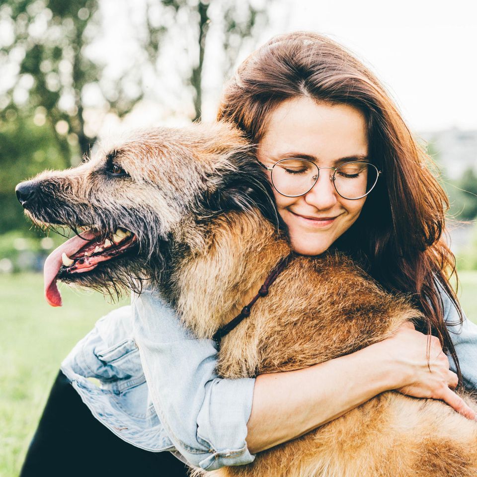 Lächelnde Frau umarmt ihren Hund