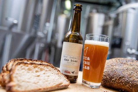 Eine Flasche Brotbier steht neben einem gefüllten Glas zwischen Brotscheiben in der Craftbier-Brauerei Orca Brau. Die Brauerei braut Bier aus Brot, welches sonst in der Mülltonne landen würde. Etwa 30 Prozent des Braumalzes werden mit Brot ersetzt, welches in den 35 Filialen der Bäckerei Feihl in der Region nicht verkauft wurde