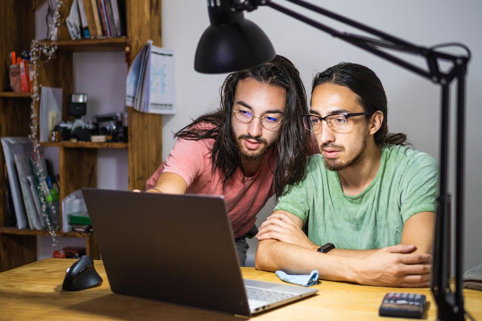 Junge Zwillingsbrüder schauen gemeinsam auf den Bildschirm eines Laptops