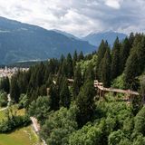 Baumwipfelpfad Senda dil Dragun mit Stadt im Hintergrund