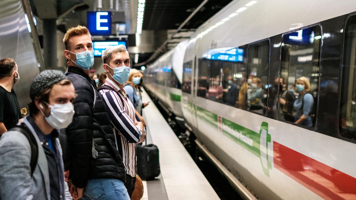 Menschen tragen Masken und stehen am Bahnsteig