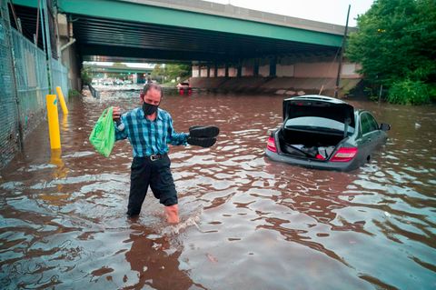 USA, Newark: Ein Mann watet durch das Hochwasser einer überschwemmten Straße während einer Sturzflut in diesem Gebiet.