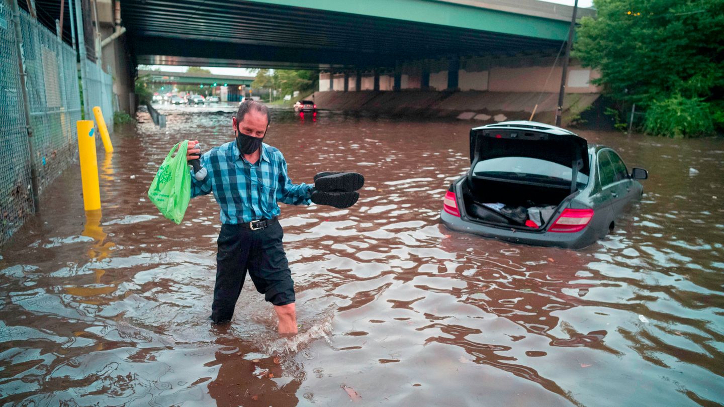 USA, Newark: Ein Mann watet durch das Hochwasser einer überschwemmten Straße während einer Sturzflut in diesem Gebiet.