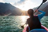 Frau fährt mit dem Kayak über den großen Hatta-Stausee im Abendlicht