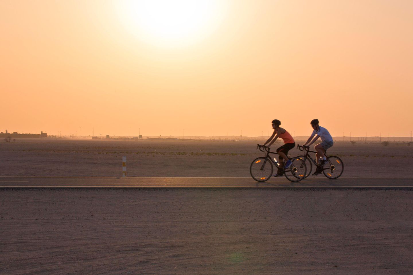 Zwei Radfahrer fahren über den Al Qudra Cycling Track in der Wüste Dubais