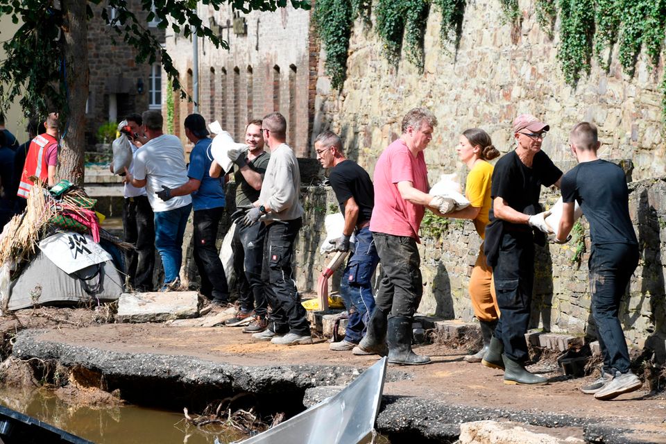 Mit einer Menschenkette befördern Helfende in Bad Münstereifel Sandsäcke an das Ufer der Erft. In der Nacht zum 15. Juli 2021 verwüstete Hochwasser  den historischen Kern der Stadt in Nordrhein-Westfalen. Straßen und Geschäfte wurden überflutet. Gas-, Strom und Telefonleitungen beschädigt