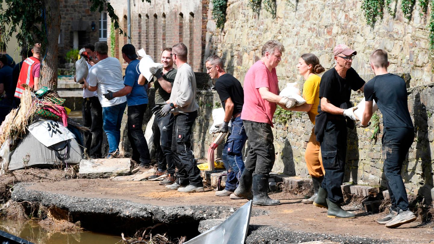 Katastrophen-Forschung: Mit einer Menschenkette befördern Helfende in Bad Münstereifel Sandsäcke an das Ufer der Erft. In der Nacht zum 15. Juli 2021 verwüstete Hochwasser  den historischen Kern der Stadt in Nordrhein-Westfalen. Straßen und Geschäfte wurden überflutet. Gas-, Strom und Telefonleitungen beschädigt Mit einer Menschenkette befördern Helfende in Bad Münstereifel Sandsäcke an das Ufer der Erft. In der Nacht zum 15. Juli 2021 verwüstete Hochwasser  den historischen Kern der Stadt in Nordrhein-Westfalen. Straßen und Geschäfte wurden überflutet. Gas-, Strom und Telefonleitungen beschädigt
