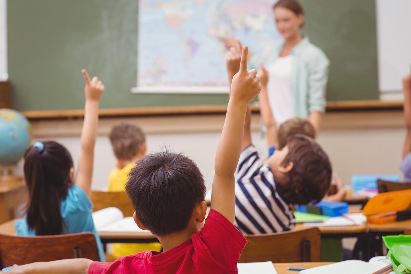 Schüler, die im Unterricht in der Grundschule die Hand heben