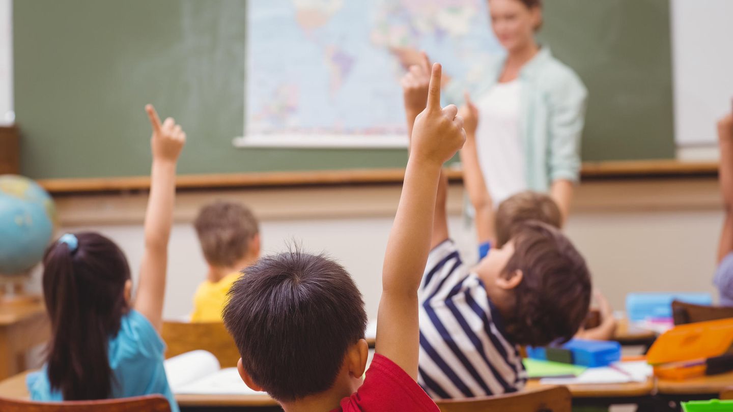 Schüler, die im Unterricht in der Grundschule die Hand heben