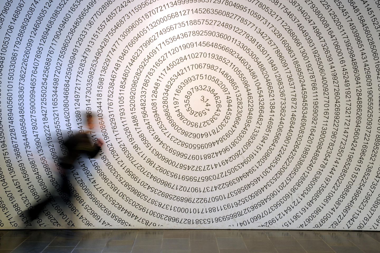 Ein Schulkind läuft im Mitmachmuseum «Mathematikum» in Gießen an der auf eine Wand geschriebenen Kreiszahl Pi vorbei