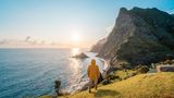 Eine Person, die bei Sonnenuntergang auf einer Klippe in Madeira, Portugal, steht