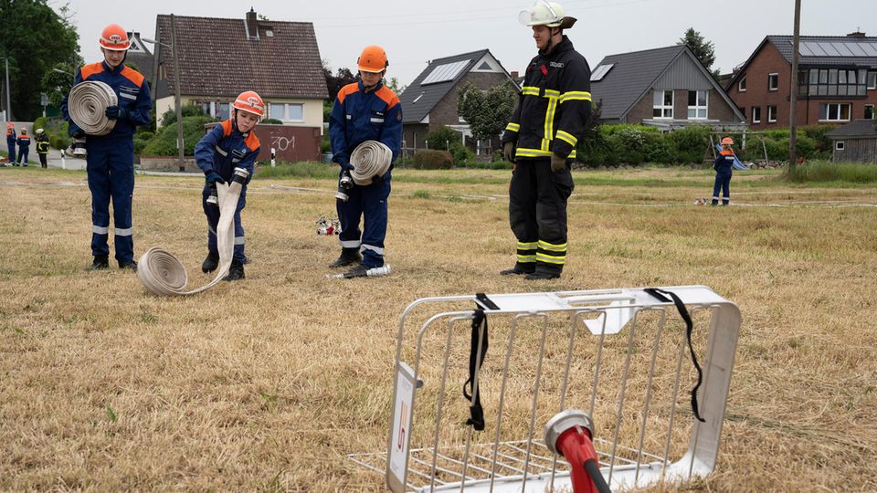 Tim versucht einen eingerollten Schlauch geradeaus ins Gitter zu rollen