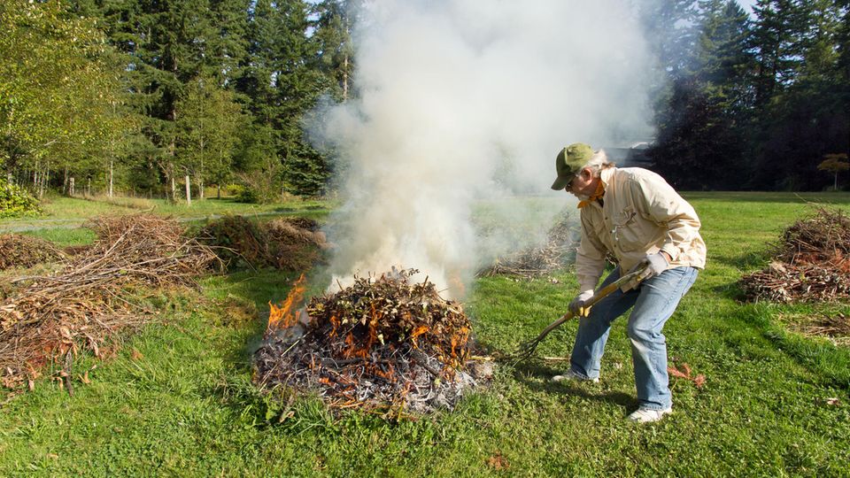 Mann verbrennt Gartenabfälle im Freien Mann verbrennt Gartenabfälle im Freien